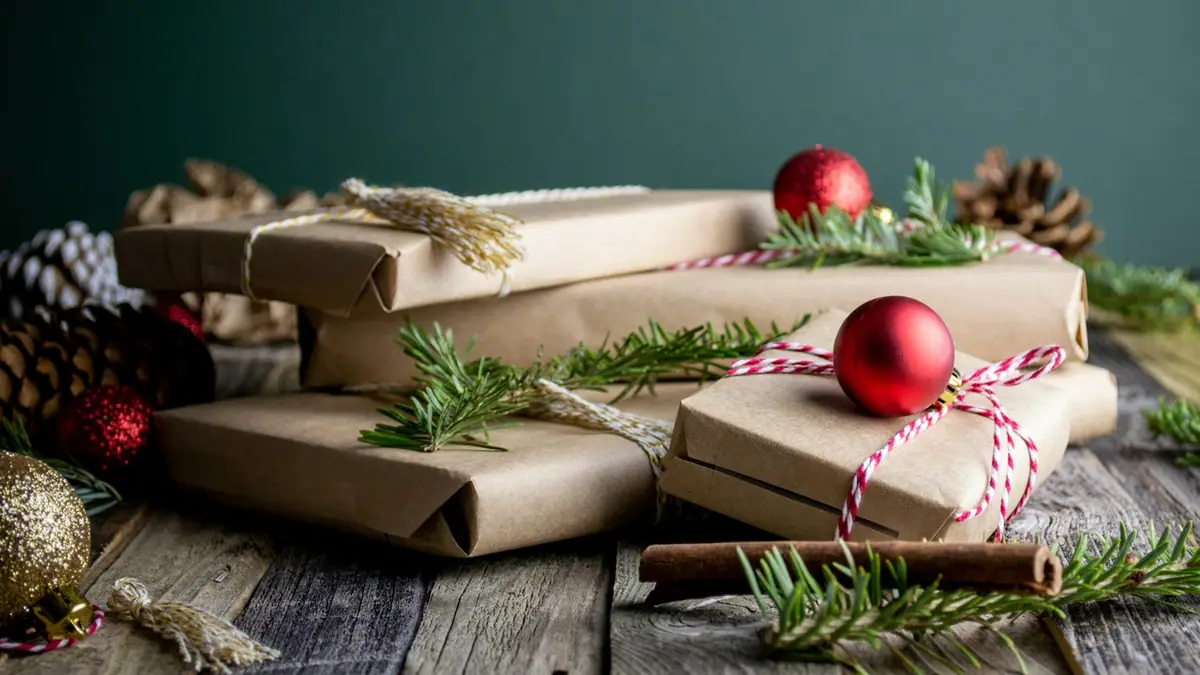 Kraft-paper Christmas gifts tied with string, with red ornaments and pine cones