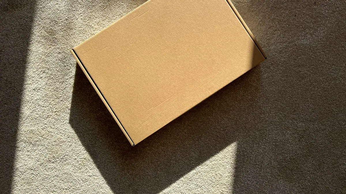 A plain cardboard parcel box on a textured surface, ready to send