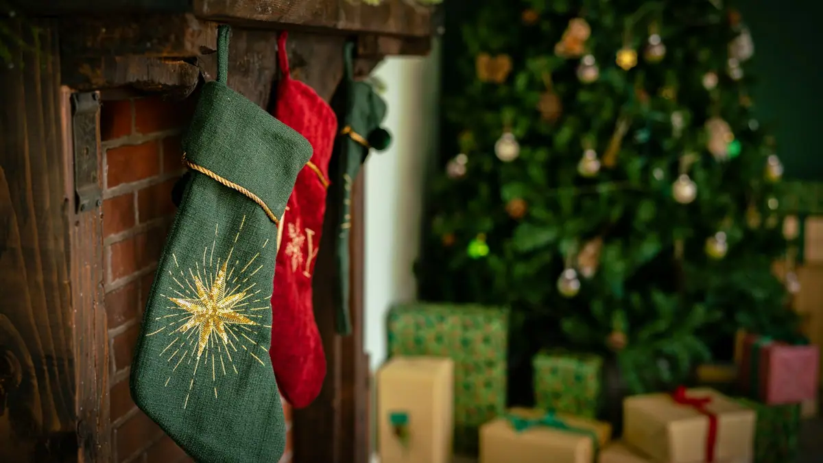 A Christmas stocking hanging from a fireplace beside a decorated tree