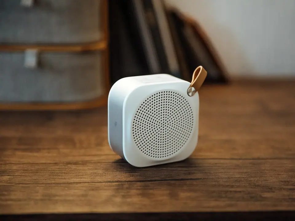 A small white portable speaker on a wooden table