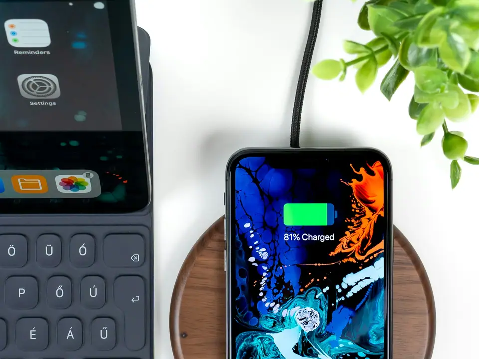 A smartphone charging on a wireless charging pad on a desk