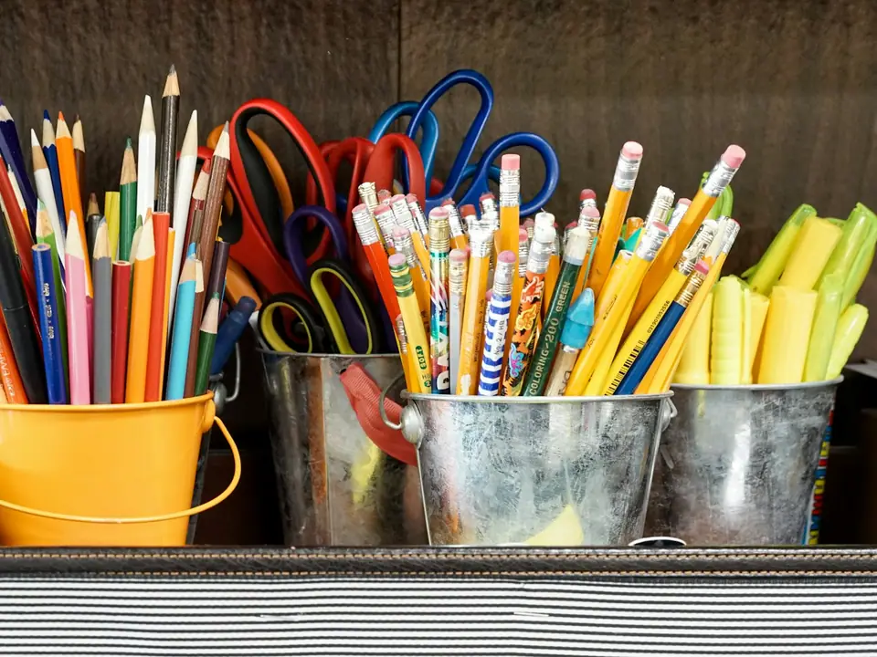 Colored pencils, scissors and highlighters in metal buckets