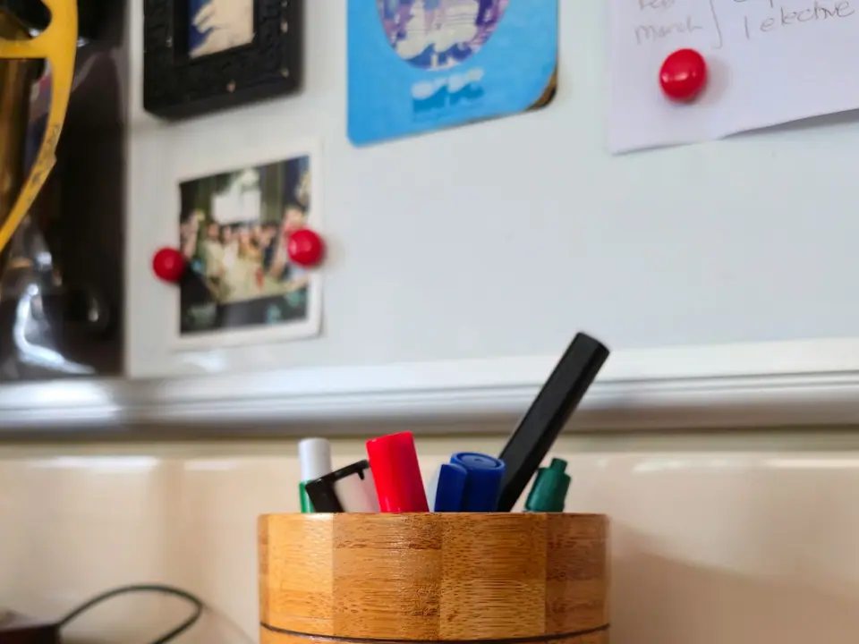 A bamboo pen holder filled with pens and markers on a desk