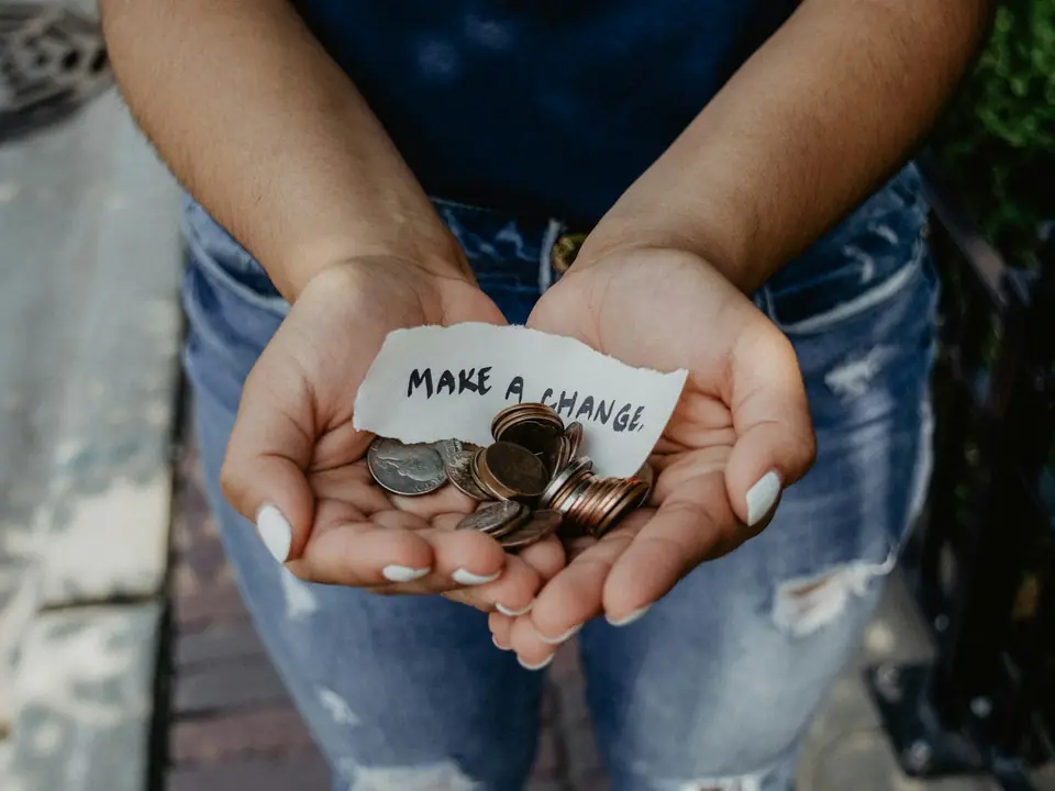 Hands holding coins and a note that says make a change