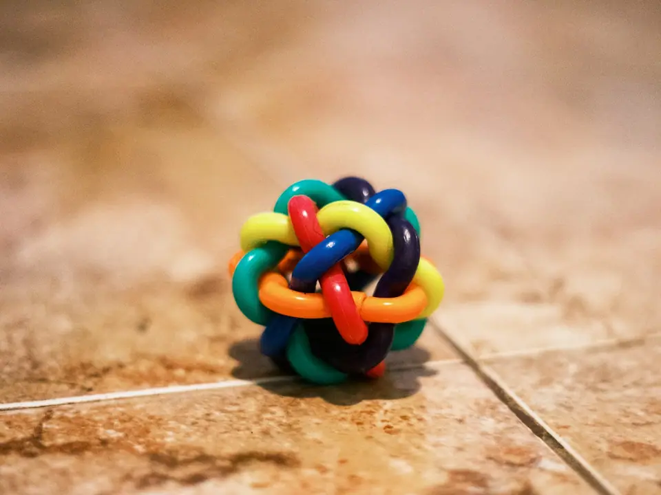 A colorful woven fidget ball on a tiled floor