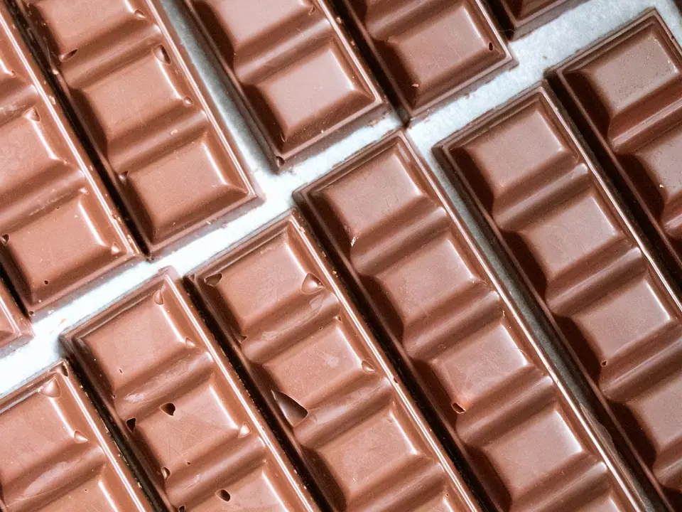 Rows of large unwrapped milk chocolate bars on a table