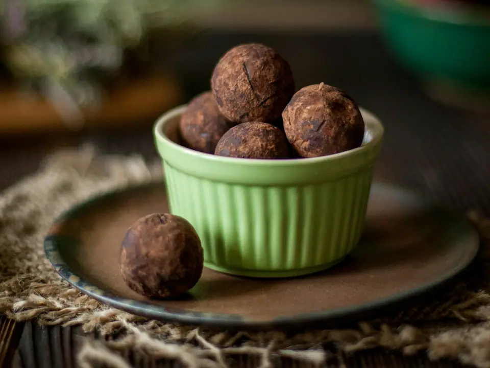 Chocolate truffles in a green bowl on a rustic table