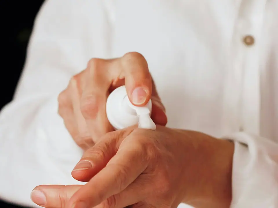 Hands applying lotion from a white pump bottle