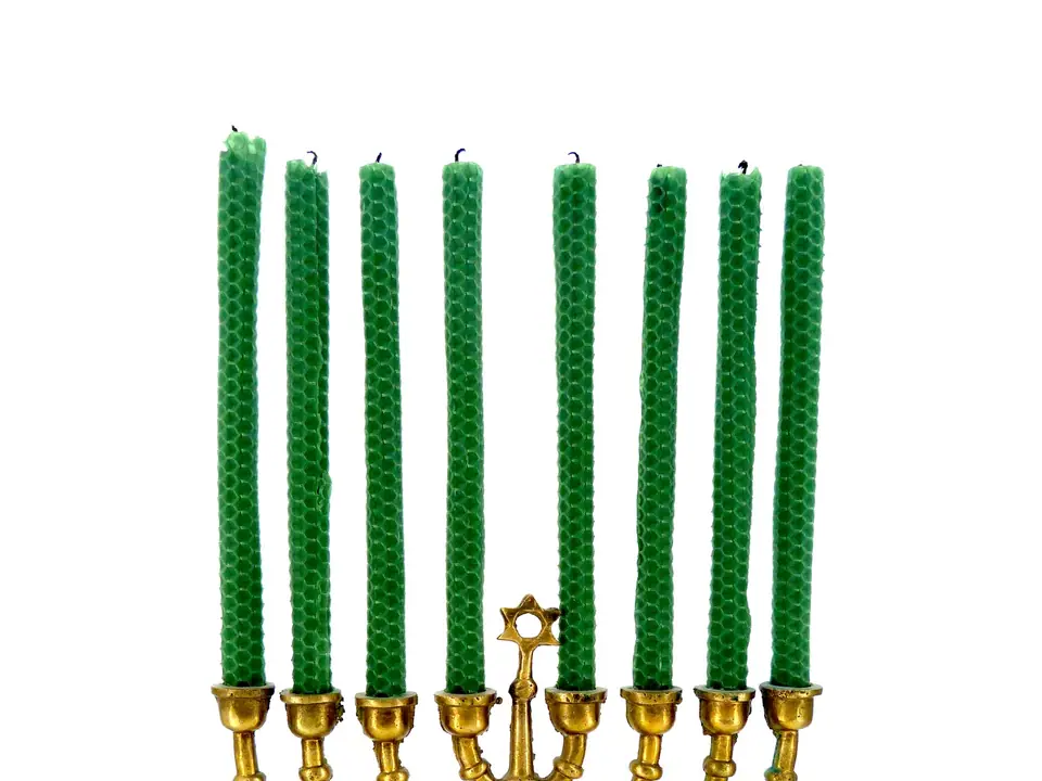 A brass menorah holding nine green beeswax candles