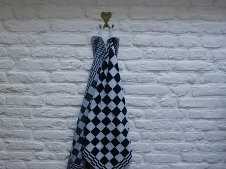 A checkered kitchen towel hanging on a white wall