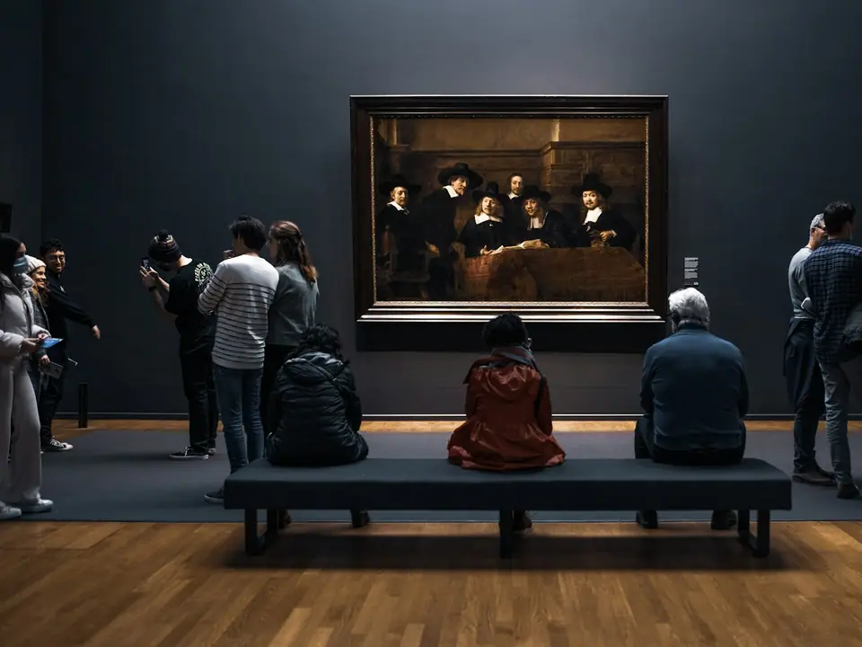Visitors looking at a large painting in a museum gallery