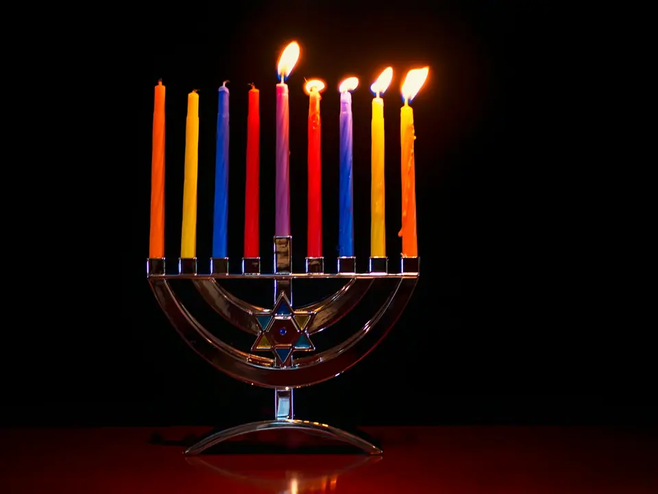 A menorah with colorful lit candles in the dark