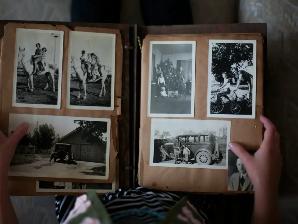 Hands opening a family photo album of black-and-white photos