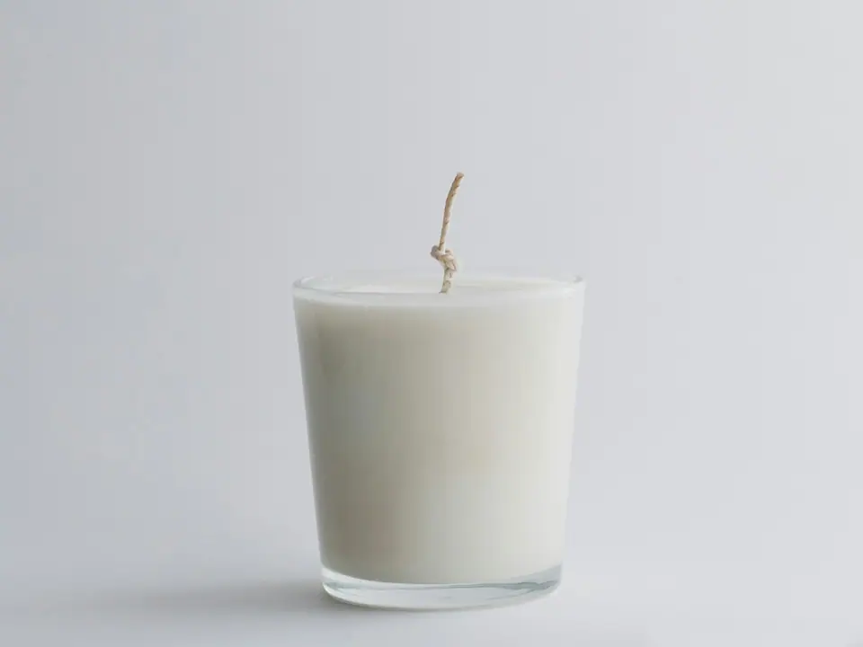 A white candle in a clear glass jar