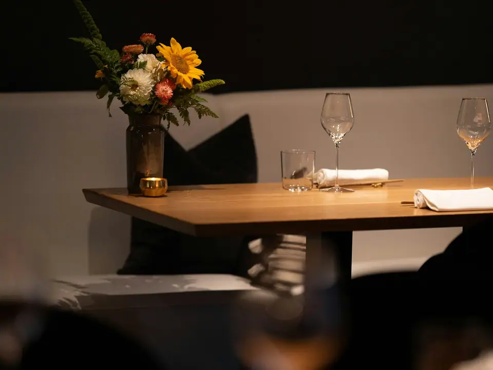 A restaurant table set with flowers and wine glasses
