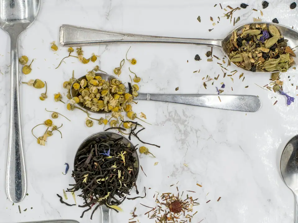 Spoons holding different loose-leaf teas on marble