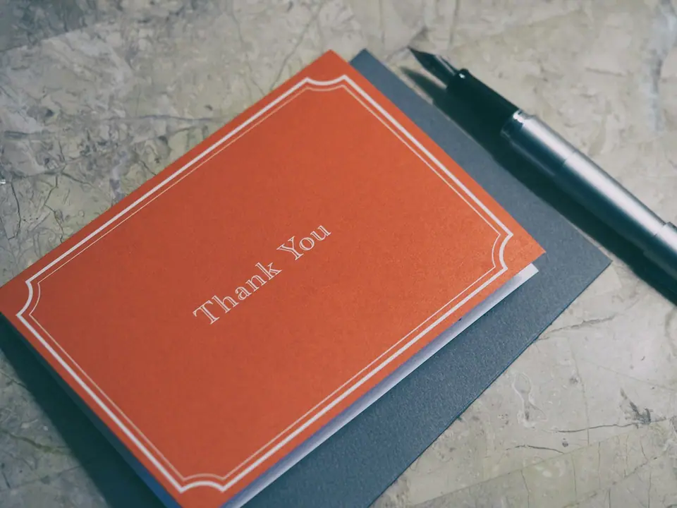 A red Thank You journal beside a fountain pen