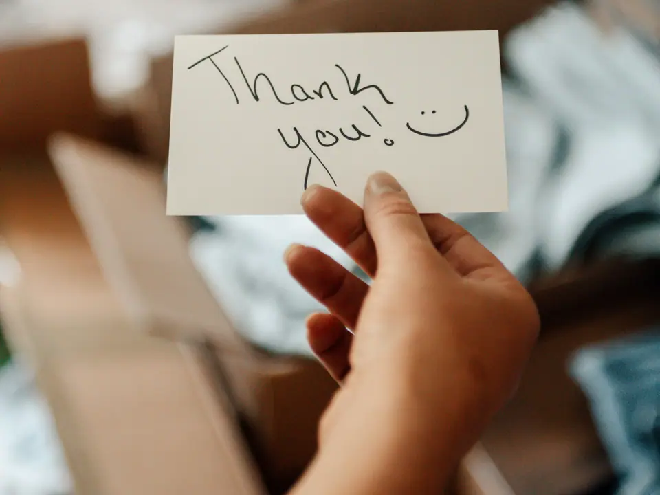 A hand holding a handwritten thank-you note