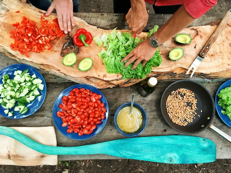 Hands slicing vegetables while preparing a meal together