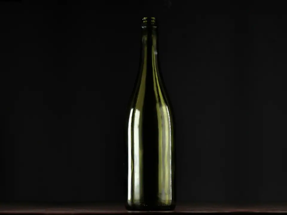 A plain glass bottle against a dark background